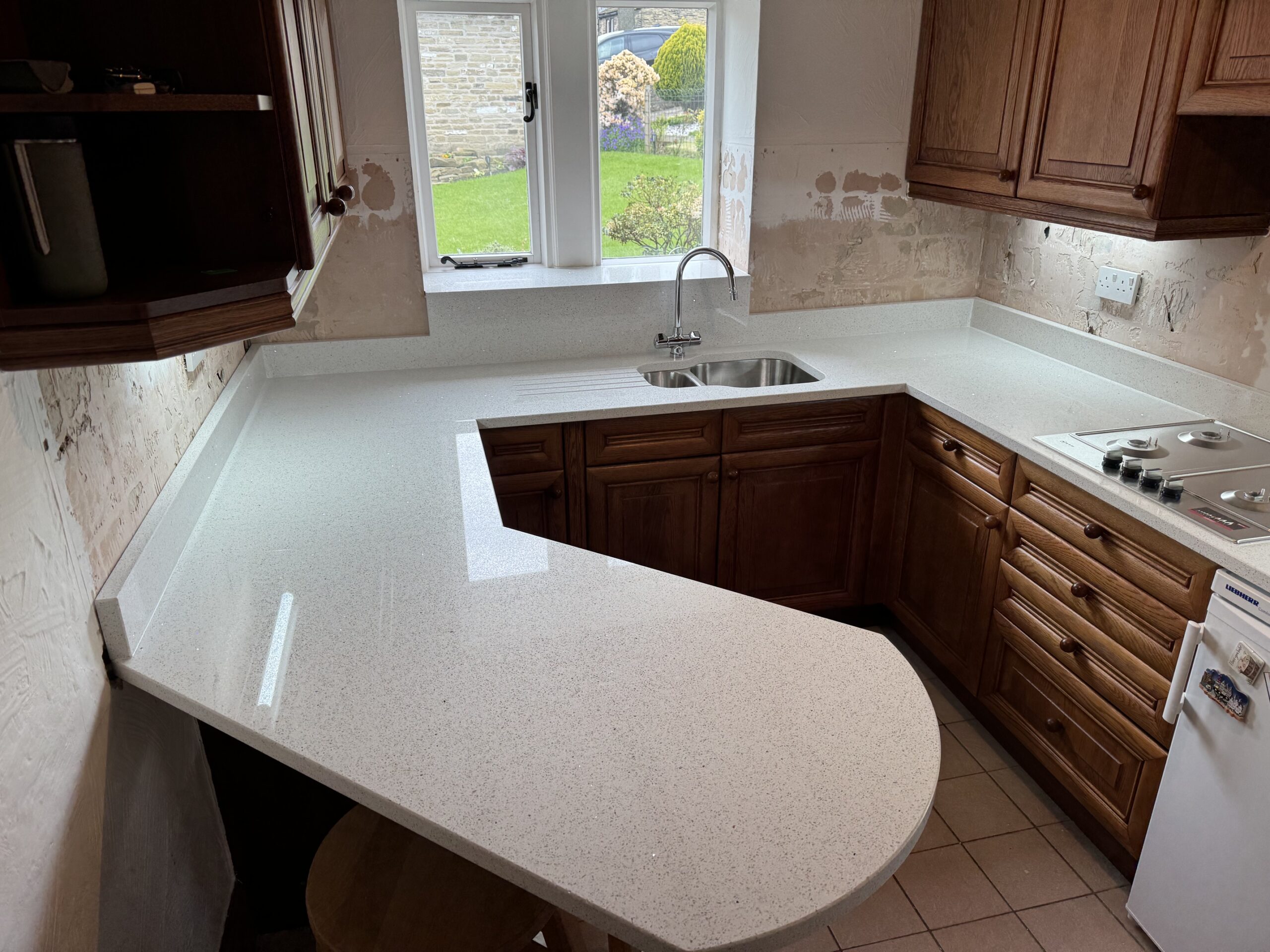 White speckled mirror quartz breakfast bar with curved seating edge and sink shelf in Huddersfield