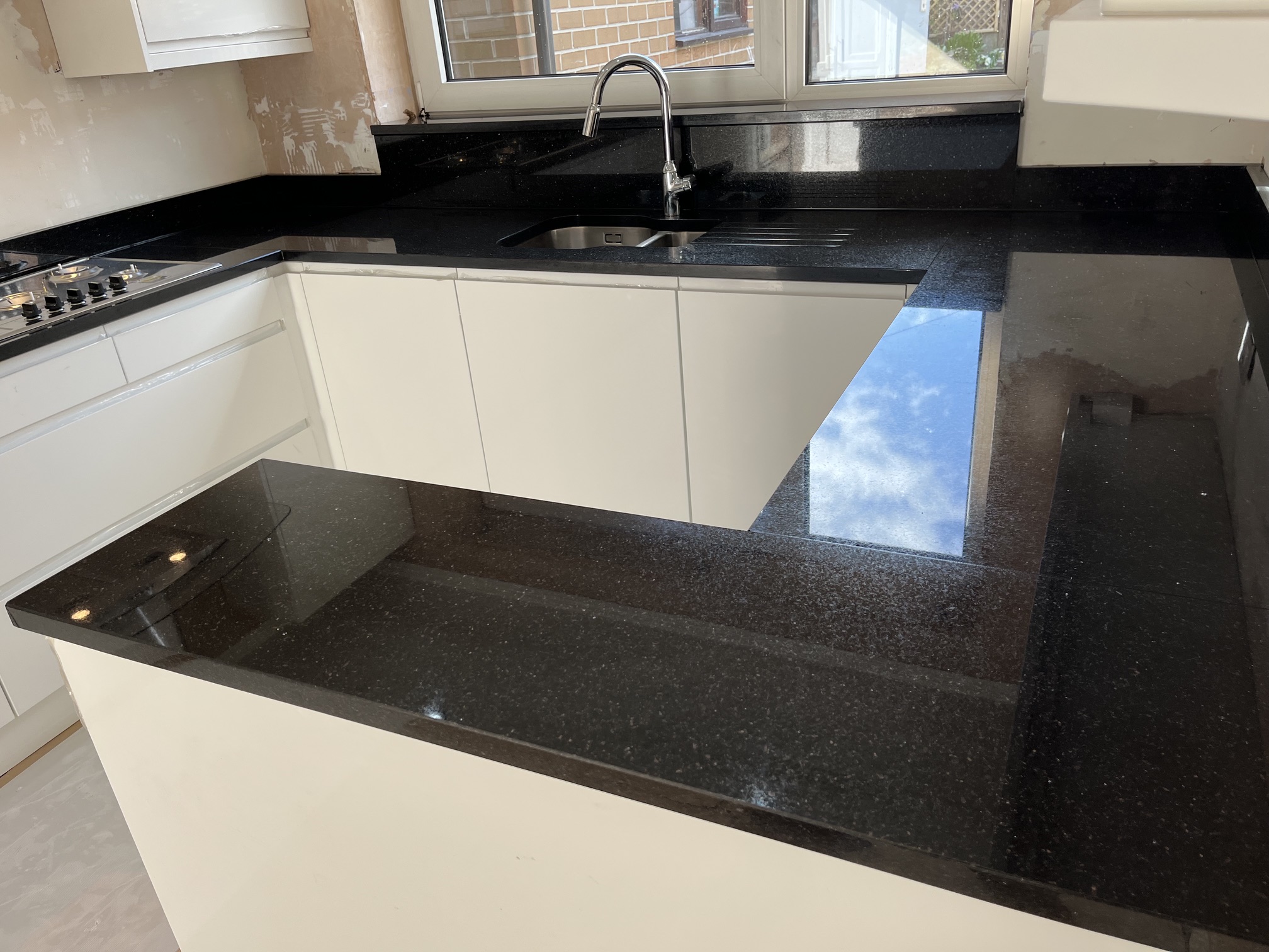 Natural black granite worktops with sink-area cladding and shelf in Guiseley