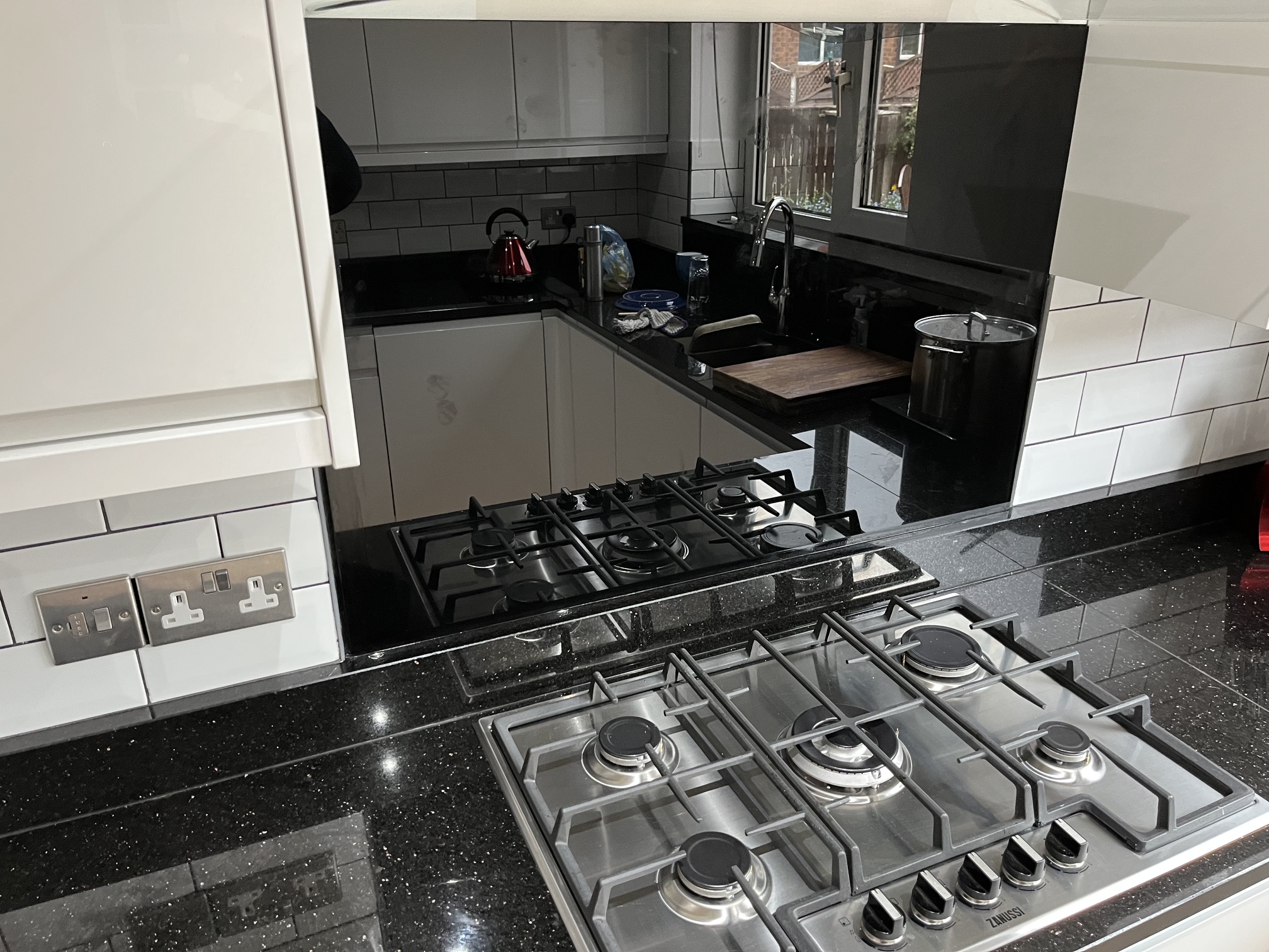 Star Galaxy granite worktop with a large smoked black glass splashback behind a gas hob in Wakefield.