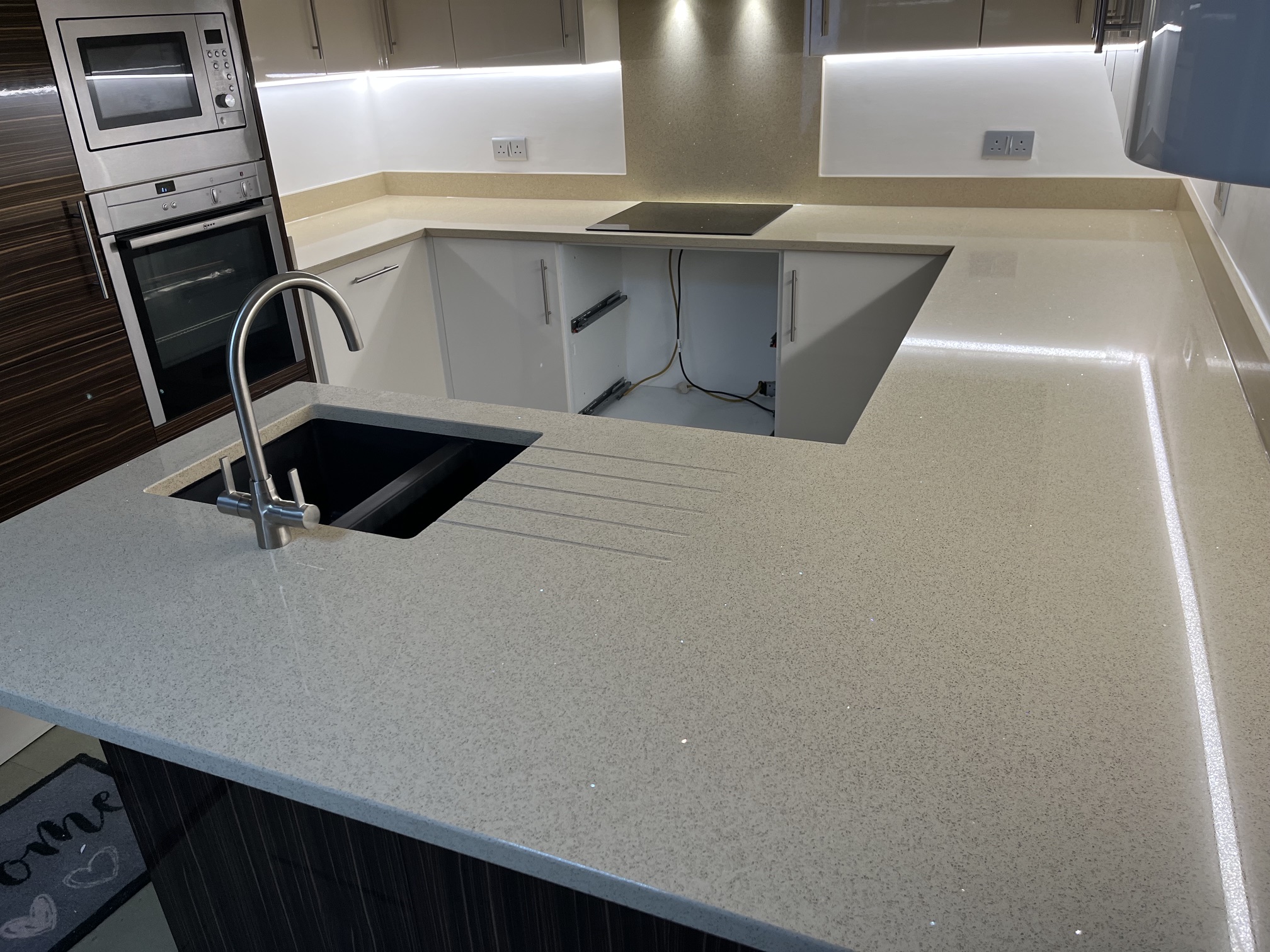 Beige mirror-fleck quartz worktops with draining grooves and full-height hob splashback in Pudsey