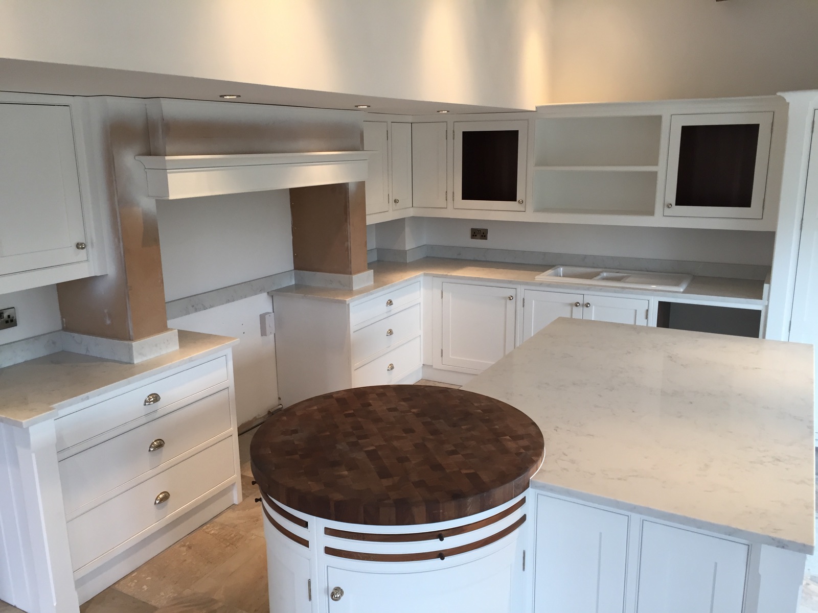 Carrera White quartz kitchen worktops and island meeting a round oak chopping board, with matching upstands and a white sit-on sink in Huddersfield.