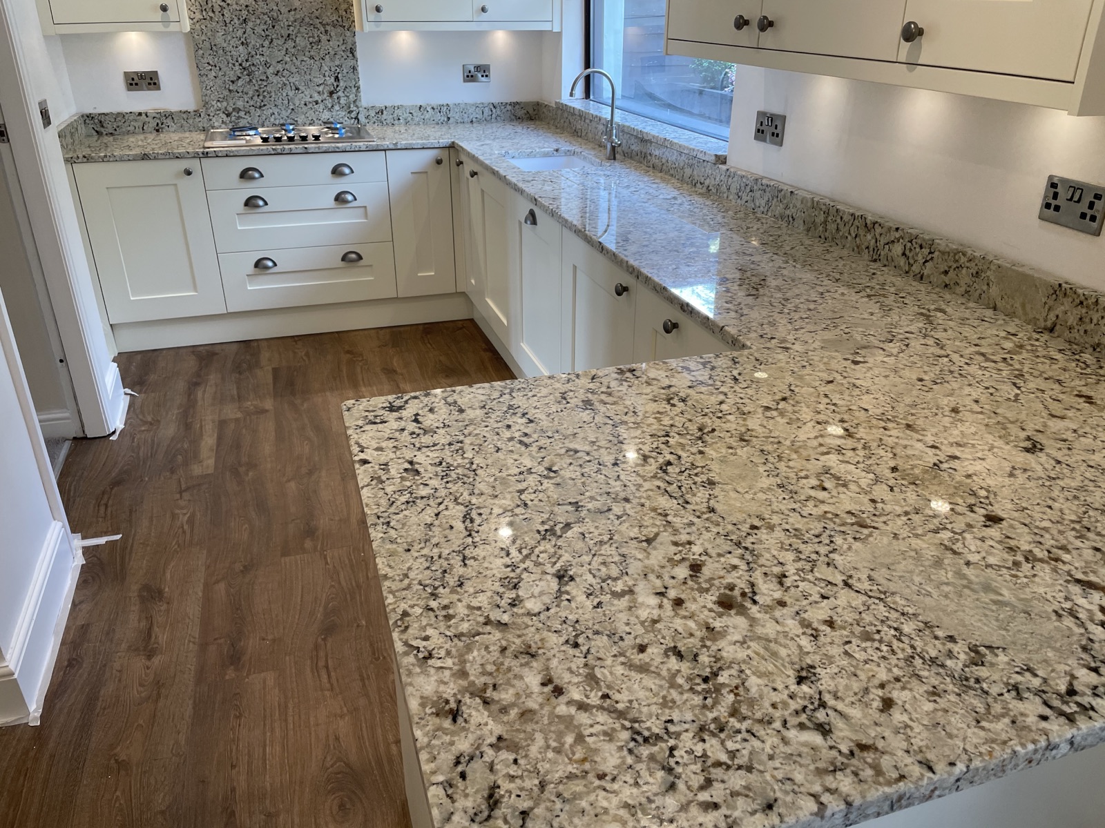 Giallo Ornamental granite worktops with ivory kitchen units, a white undermounted sink and matching granite hob splashback in Menston.