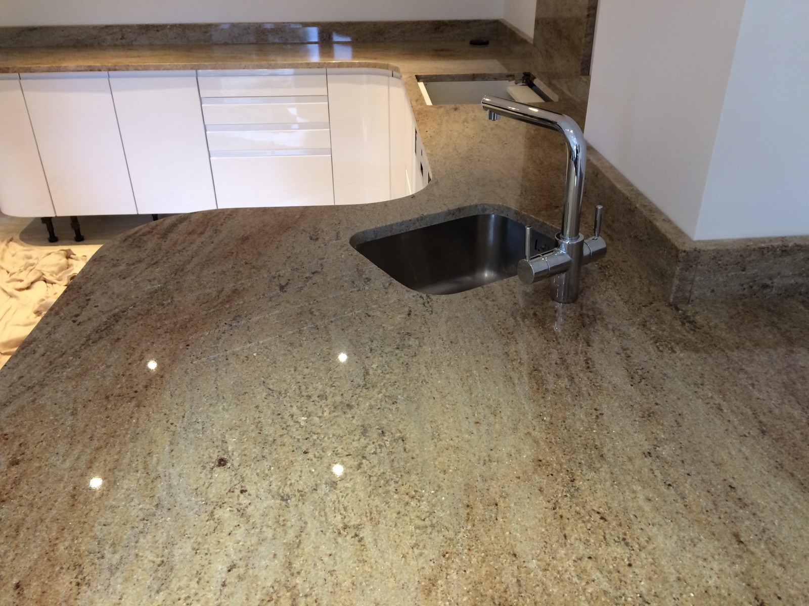 Curved Ivory Fantasy granite worktop with an undermounted stainless steel sink, angled draining grooves and matching upstands in Rawdon, Leeds.