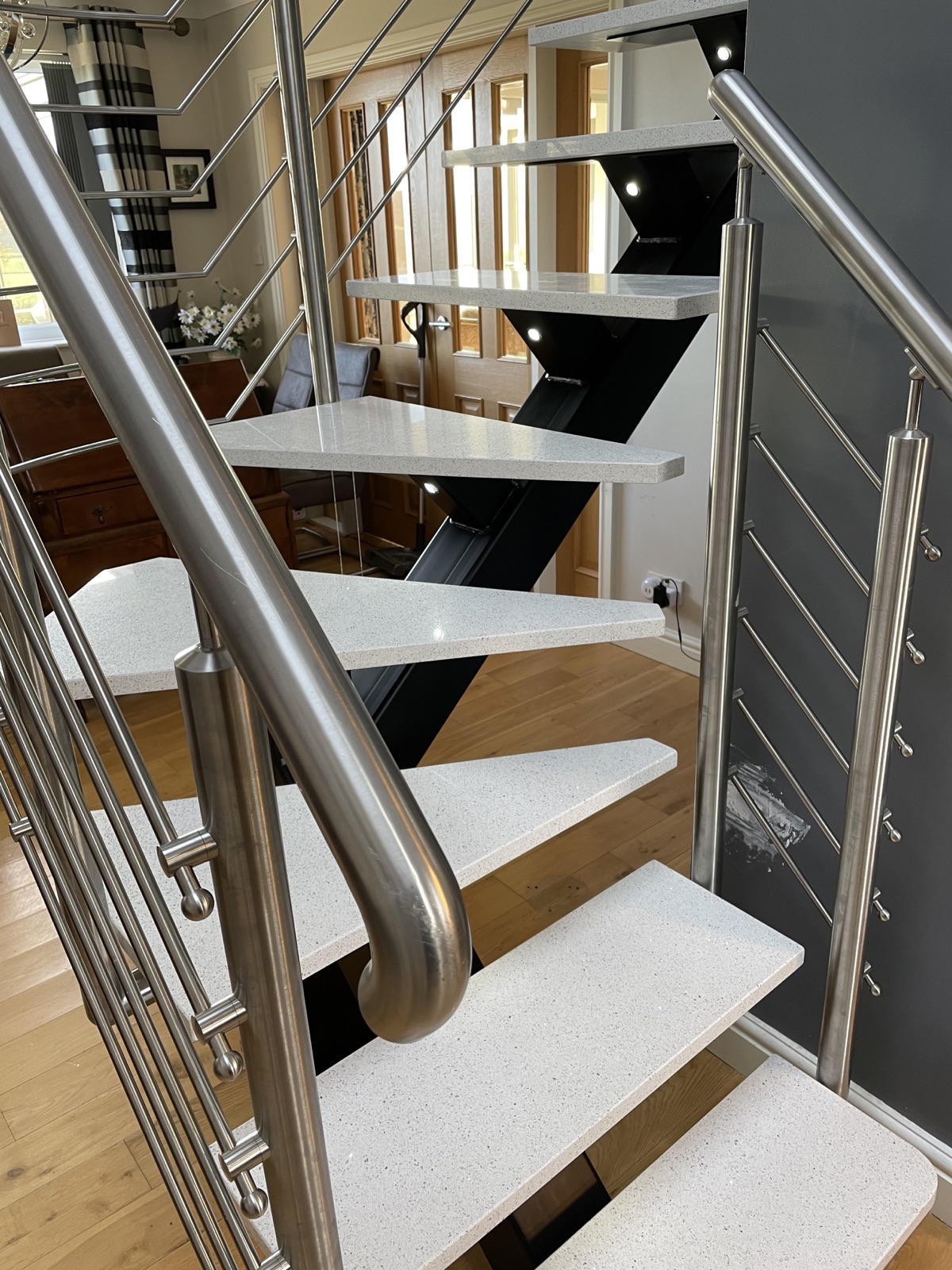 Individually shaped Stellar White quartz stair treads with stainless steel handrails in Honley, Huddersfield.